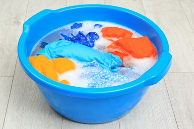 Photo of Basin with colorful clothes on floor. Hand washing laundry
