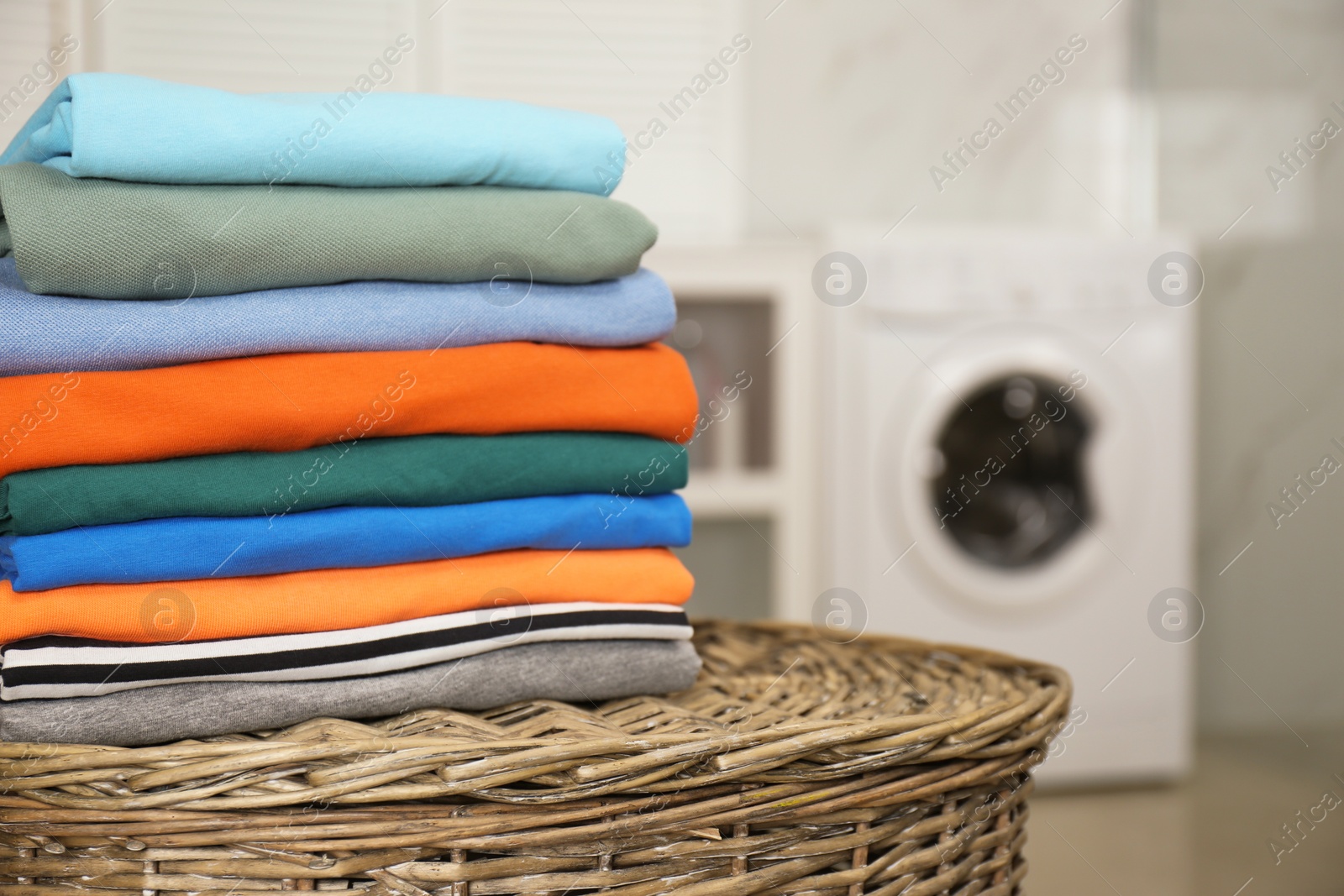 Photo of Stack of fresh laundry on basket in bathroom. Space for text