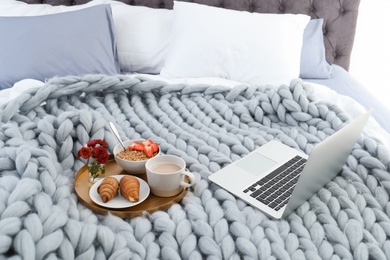 Photo of Laptop and tray with breakfast on bed. Interior element