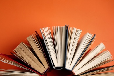 Hardcover books on orange background, flat lay