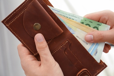 Photo of Man putting Euro banknotes in wallet, closeup