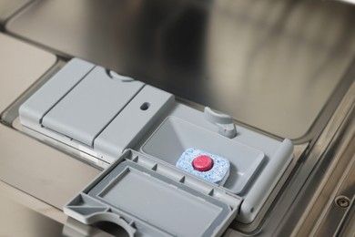 Photo of Open dishwasher door with detergent tablet, closeup