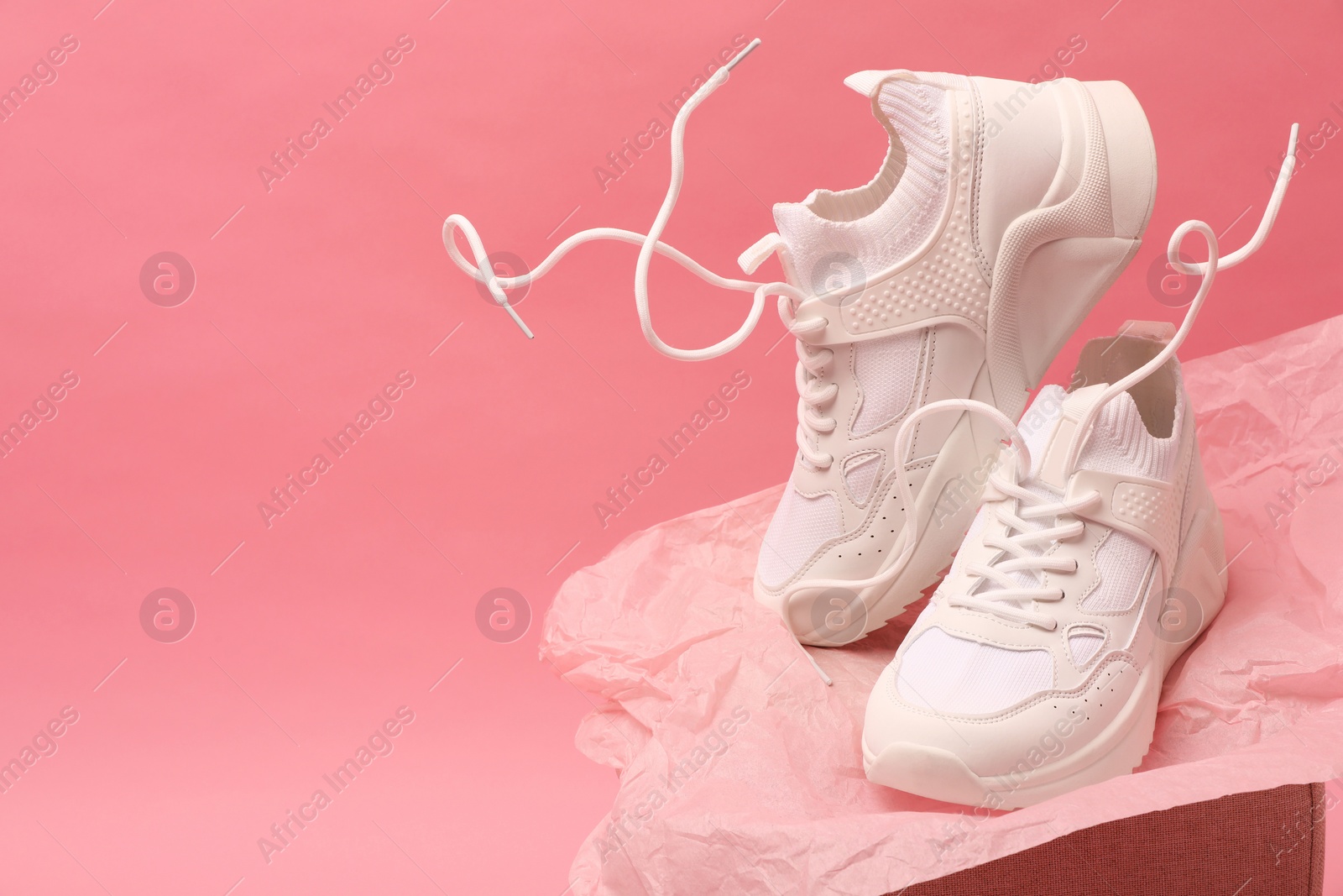 Photo of Stylish presentation of trendy sneakers on pink background. Space for text