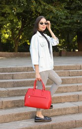 Photo of Young woman with stylish bag on stairs outdoors