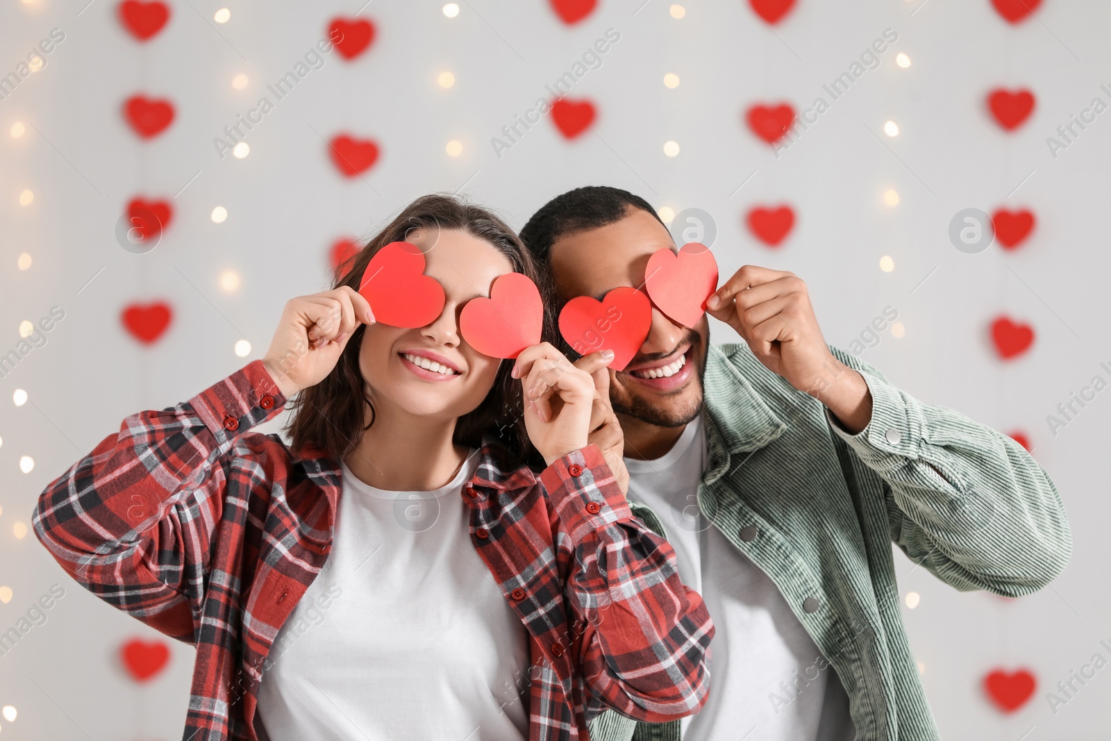 Photo of Lovely couple with red paper hearts indoors. Valentine's day celebration