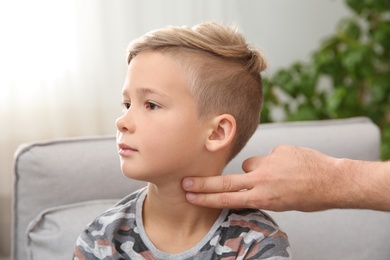 Man checking little boy's pulse with fingers indoors