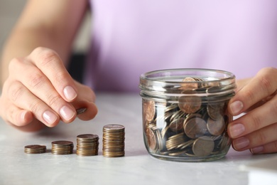 Photo of Woman stacking coins at grey marble table, closeup. Money savings