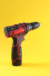 Photo of Modern cordless electric screwdriver on yellow background