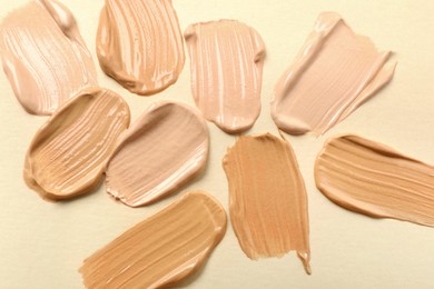 Samples of skin foundation on beige background, top view