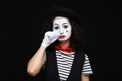 Photo of Young woman in mime costume posing on black background