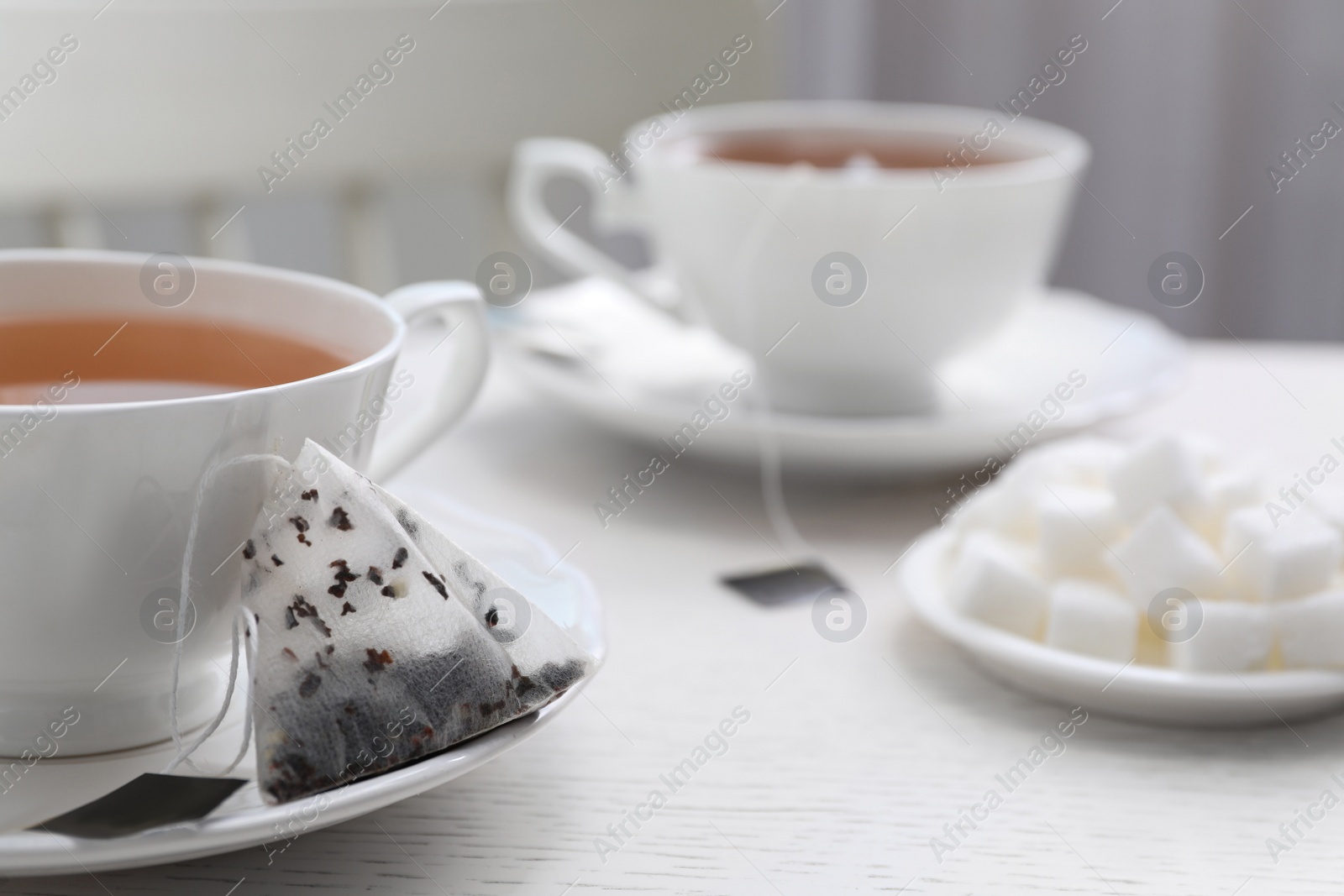 Photo of Tea bag and cup of hot drink on white wooden table, closeup. Space for text