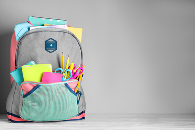 Photo of Stylish backpack with different school stationery on table against light grey background. Space for text
