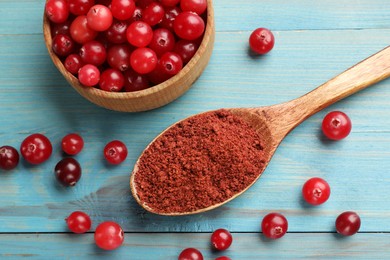 Photo of Spoon with cranberry powder and fresh berries on light blue wooden table, flat lay