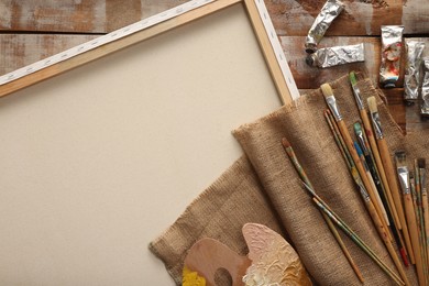 Photo of Natural burlap fabric and different painting supplies on wooden table , top view