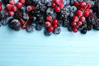 Photo of Mix of tasty frozen berries on light blue wooden table, flat lay. Space for text