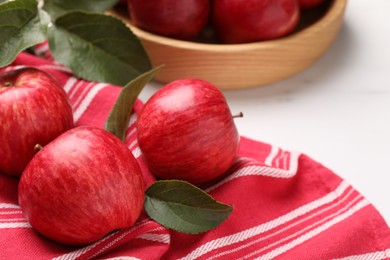 Photo of Fresh red apples with leaves on white table, closeup. Space for text