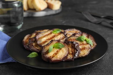 Photo of Delicious grilled eggplant slices served on black table, closeup