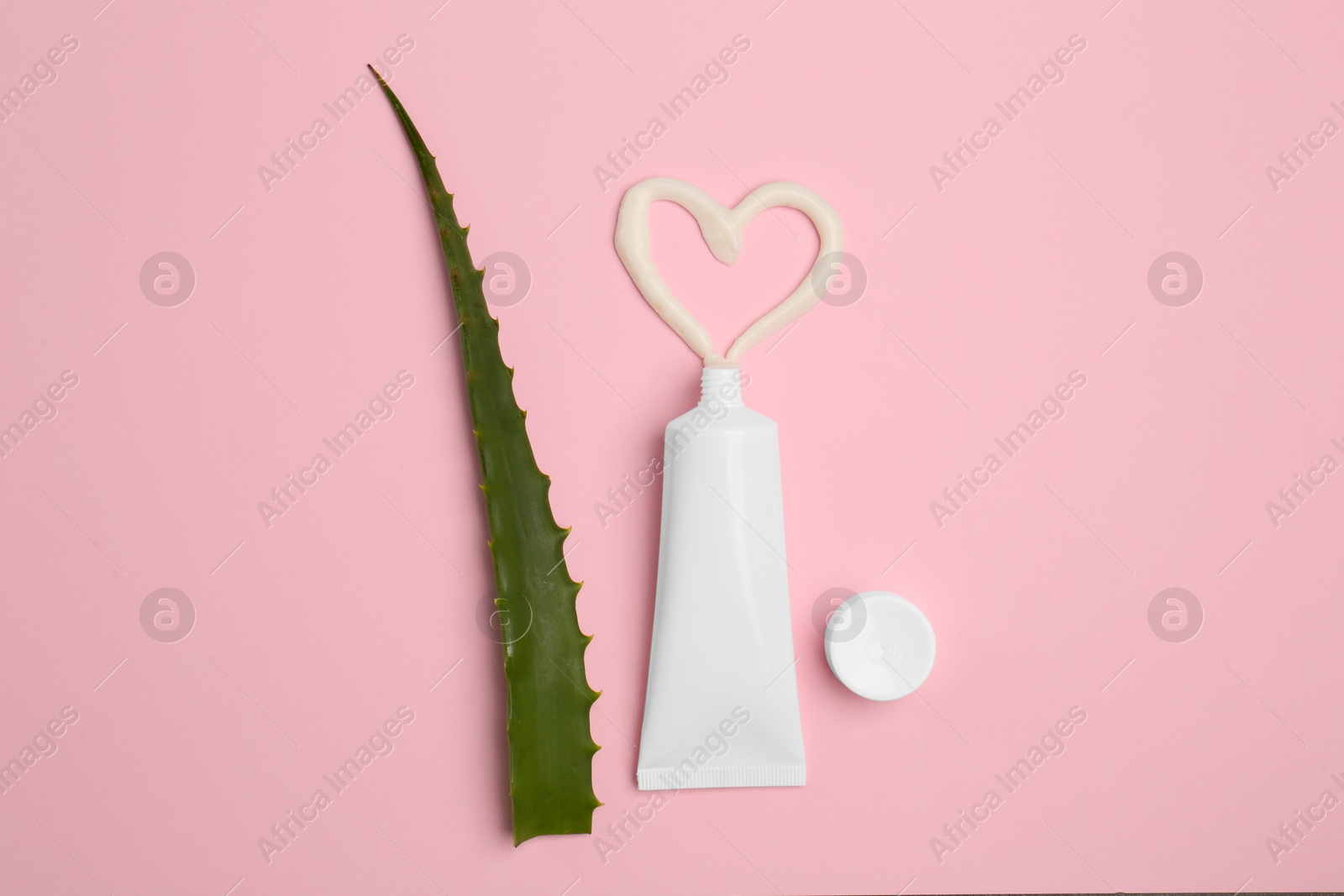 Photo of Tube of toothpaste and fresh aloe on pink background, flat lay