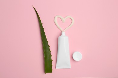 Photo of Tube of toothpaste and fresh aloe on pink background, flat lay