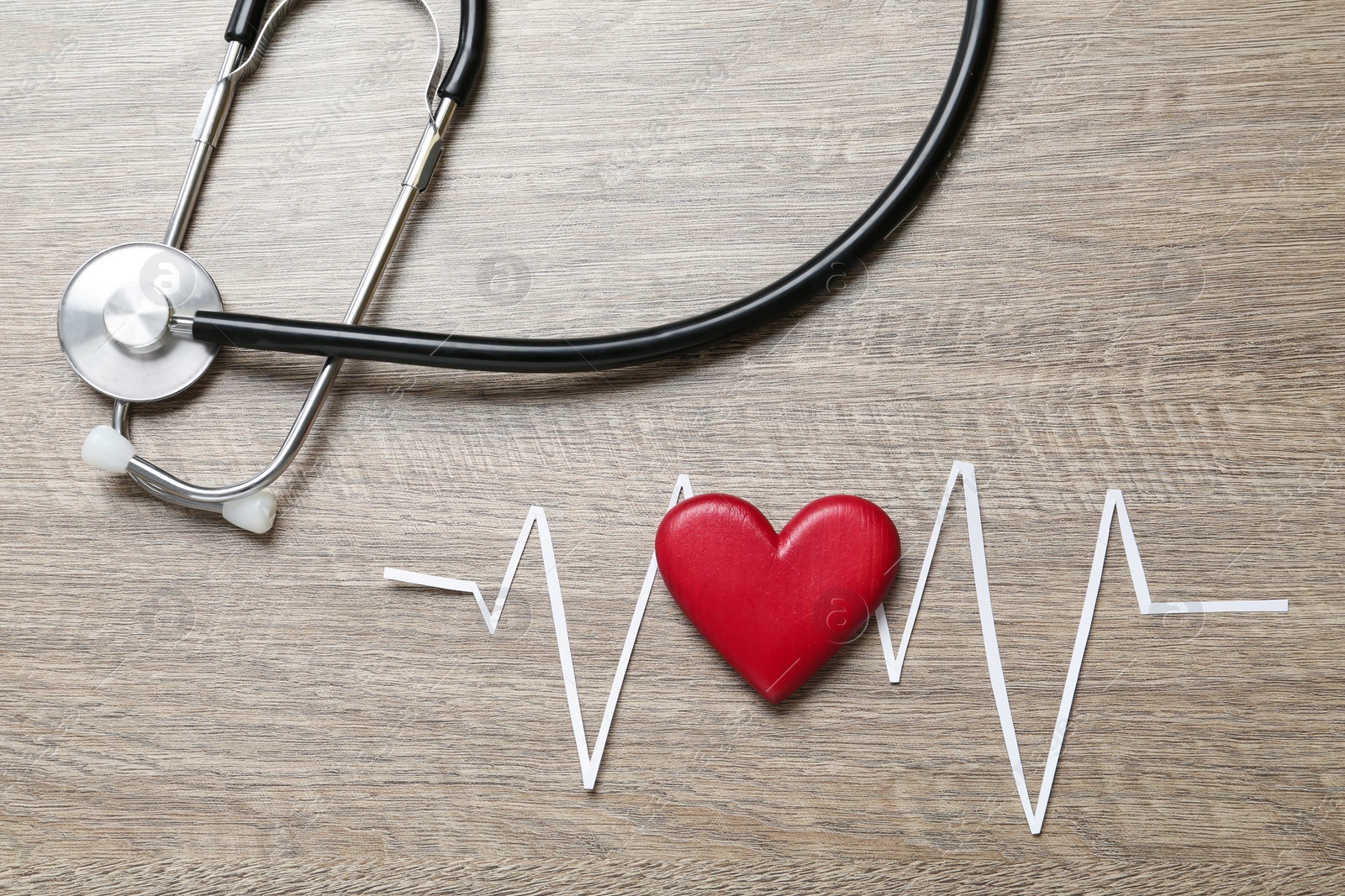 Photo of Paper cardiogram line, red heart and stethoscope on wooden table, flat lay