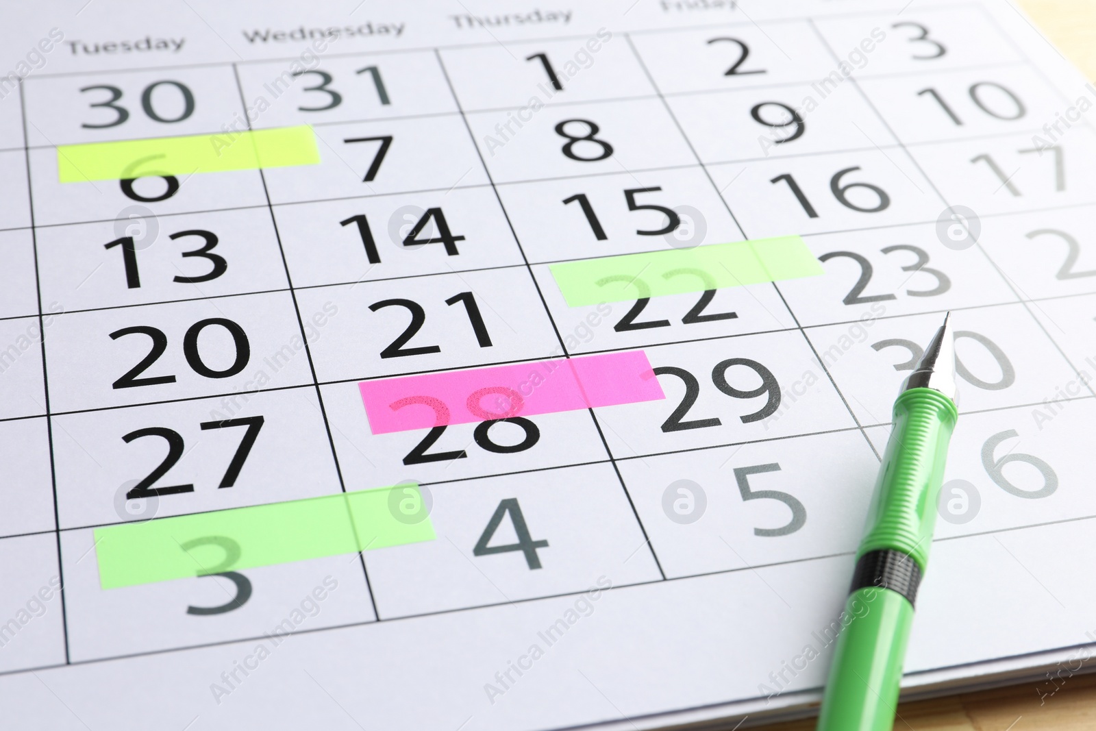 Photo of Timetable. Calendar page with marked dates and pen on table, closeup