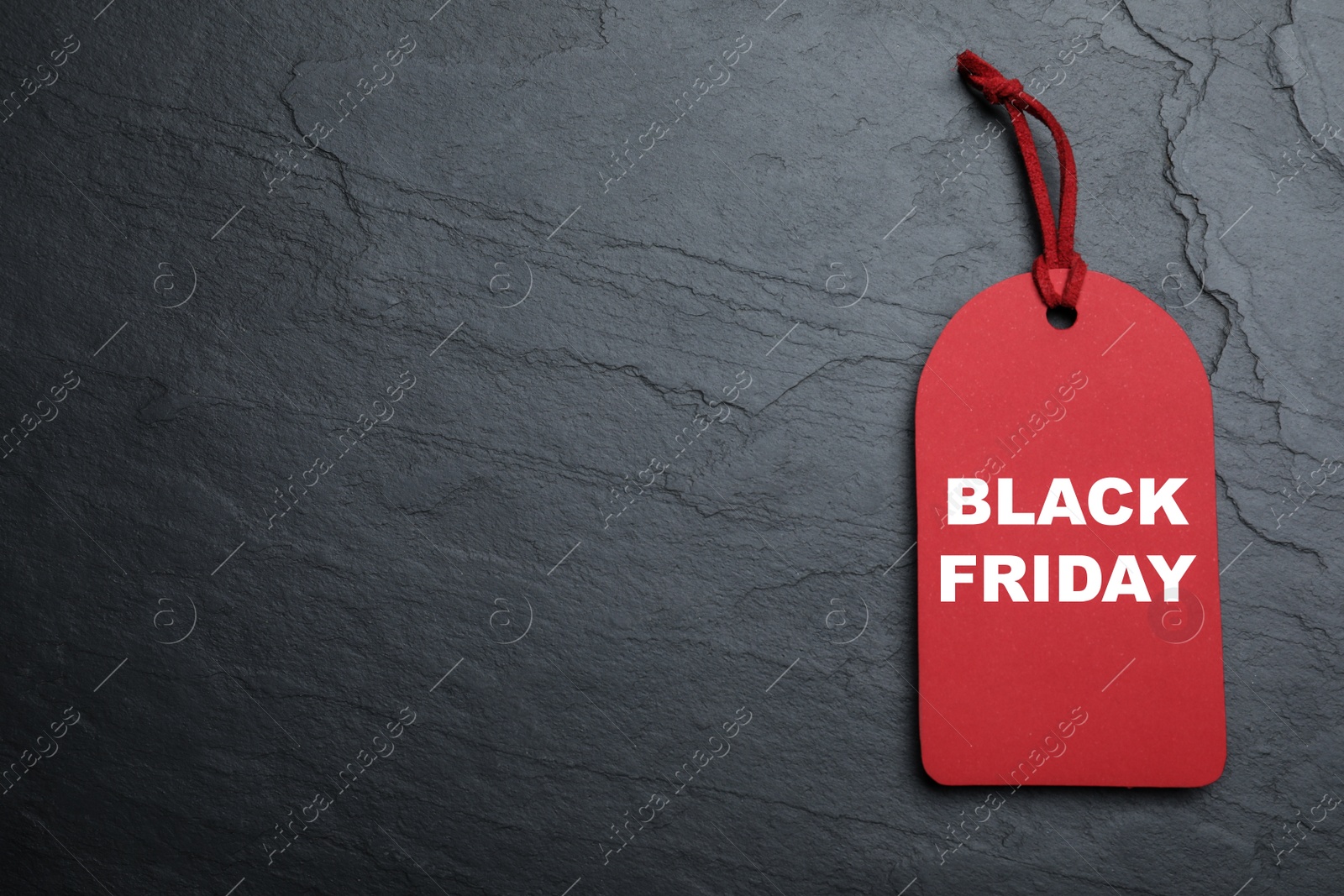 Photo of Red tag with words Black Friday on dark stone background, top view. Space for text