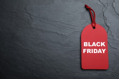 Photo of Red tag with words Black Friday on dark stone background, top view. Space for text