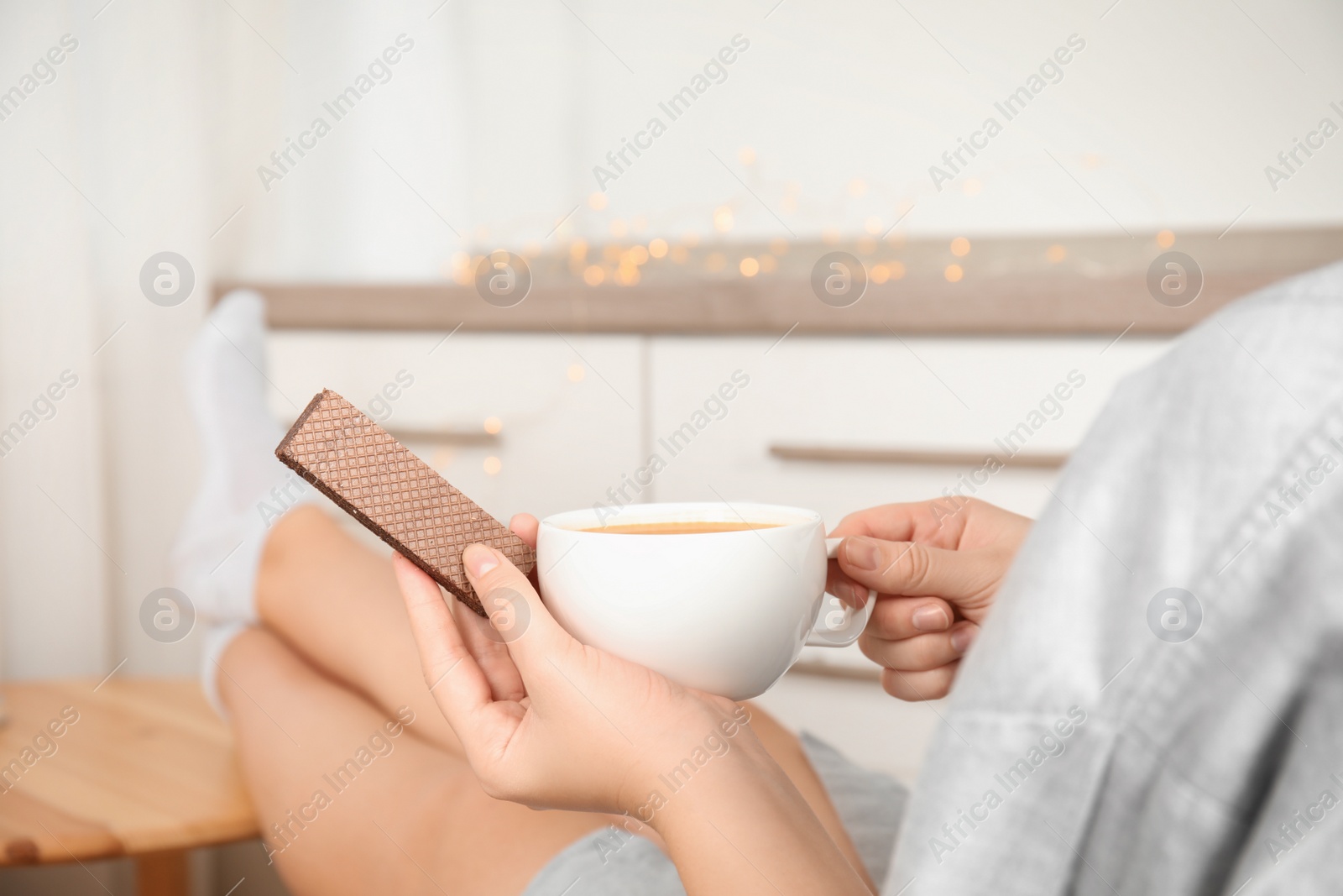 Photo of Woman having delicious wafer and coffee for breakfast indoors, closeup