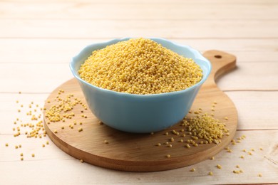 Photo of Millet groats in bowl on light wooden table
