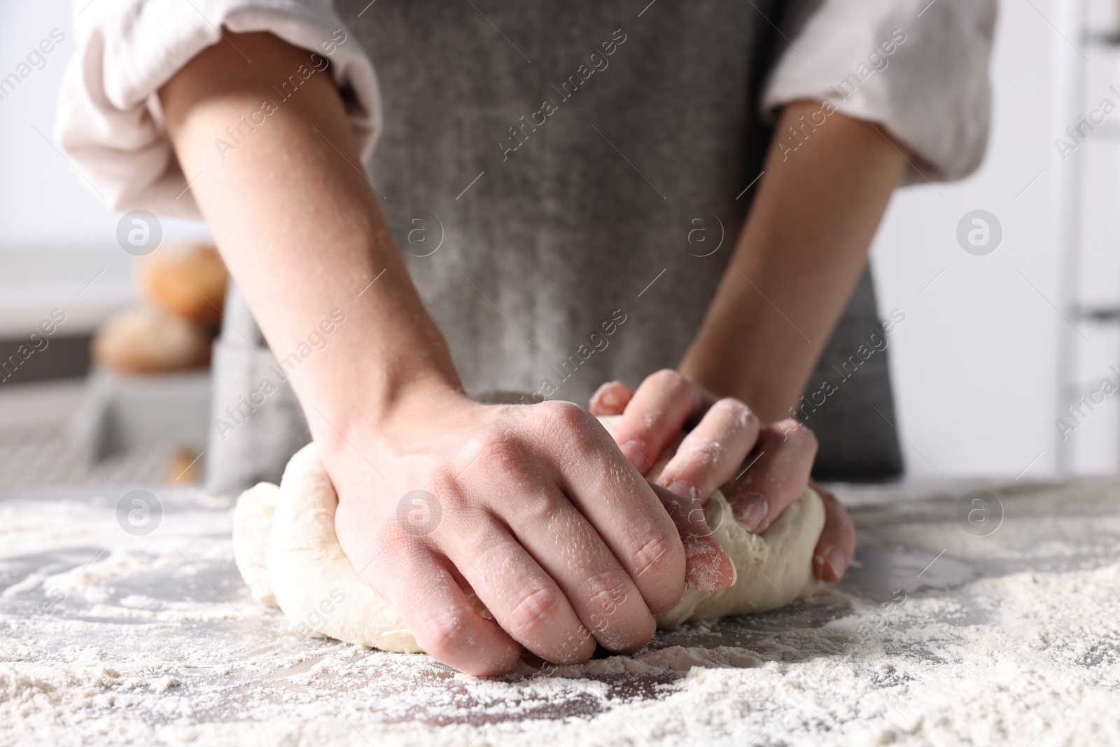 Photo of Woman kneading dough at table in kitchen, closeup