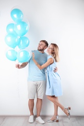 Young couple with air balloons near white wall