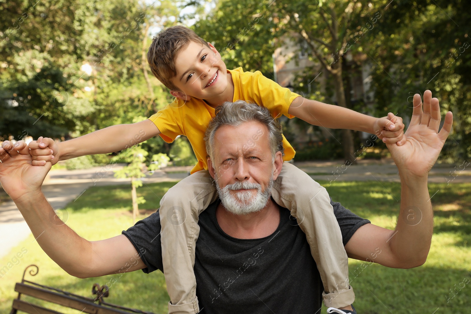 Photo of Senior man with his little grandson having fun together in park