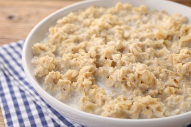 Photo of Tasty boiled oatmeal in bowl on table, closeup