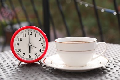 Photo of Alarm clock and cup with hot drink on table