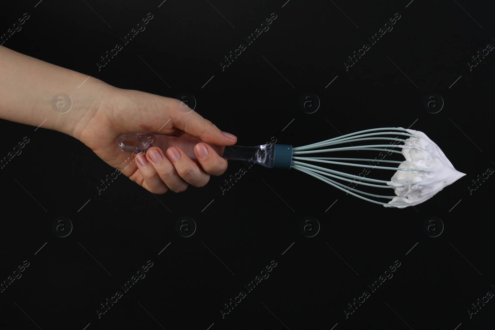 Photo of Woman holding whisk with whipped cream on black background, closeup