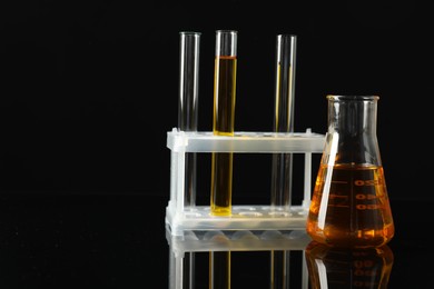 Photo of Laboratory glassware with different types of oil on black background. Space for text
