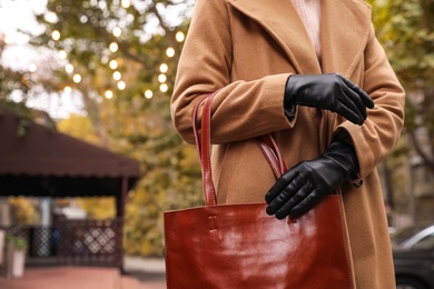 Photo of Young woman in black leather gloves, closeup. Stylish clothes