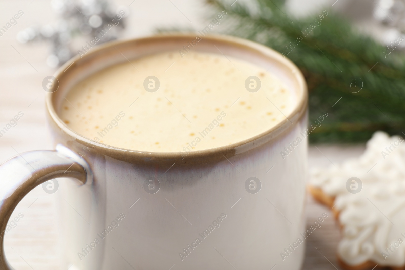 Photo of Cup of delicious eggnog on table, closeup