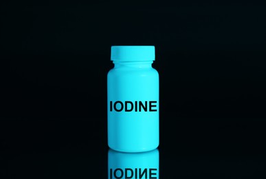 Photo of Plastic container of medical iodine on black background, color tone effect