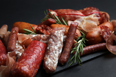 Photo of Different types of sausages served on black background, closeup