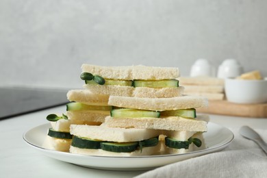 Tasty sandwiches with cucumber, butter and microgreens on white table indoors, closeup