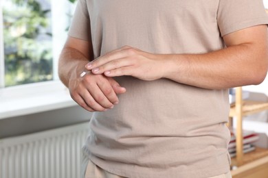 Photo of Man applying hand cream at home, closeup