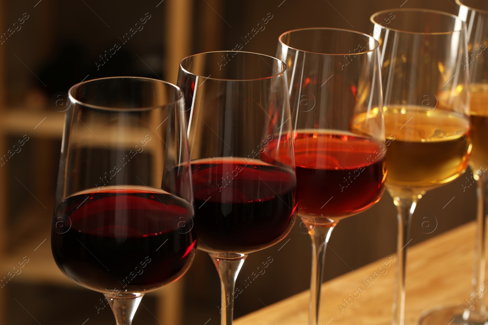 Photo of Glasses of different wines against blurred background, closeup. Expensive collection