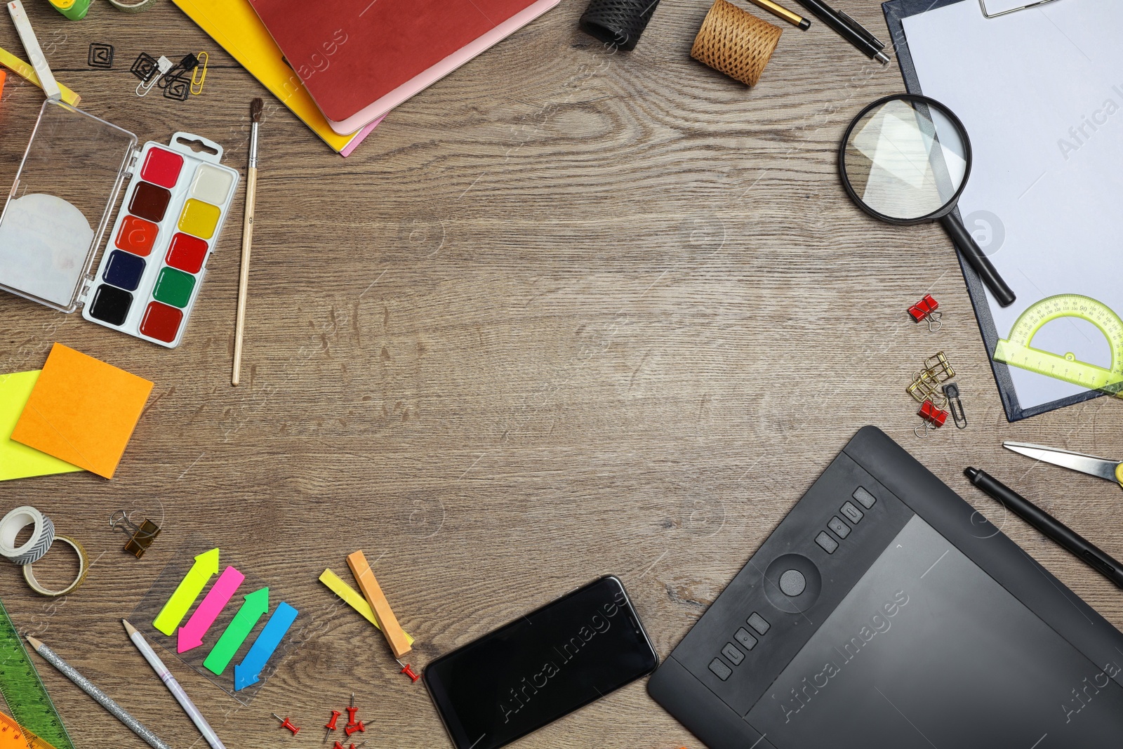 Photo of Flat lay composition with graphics tablet and stationery on wooden table, space for text. Designer's workplace