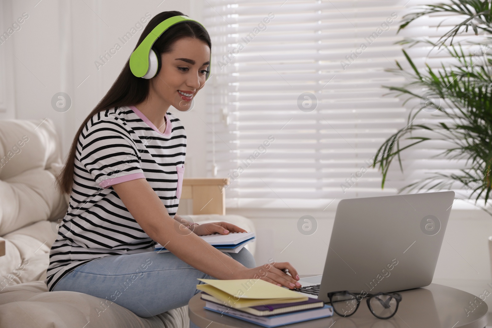 Photo of Young woman watching webinar on sofa at home