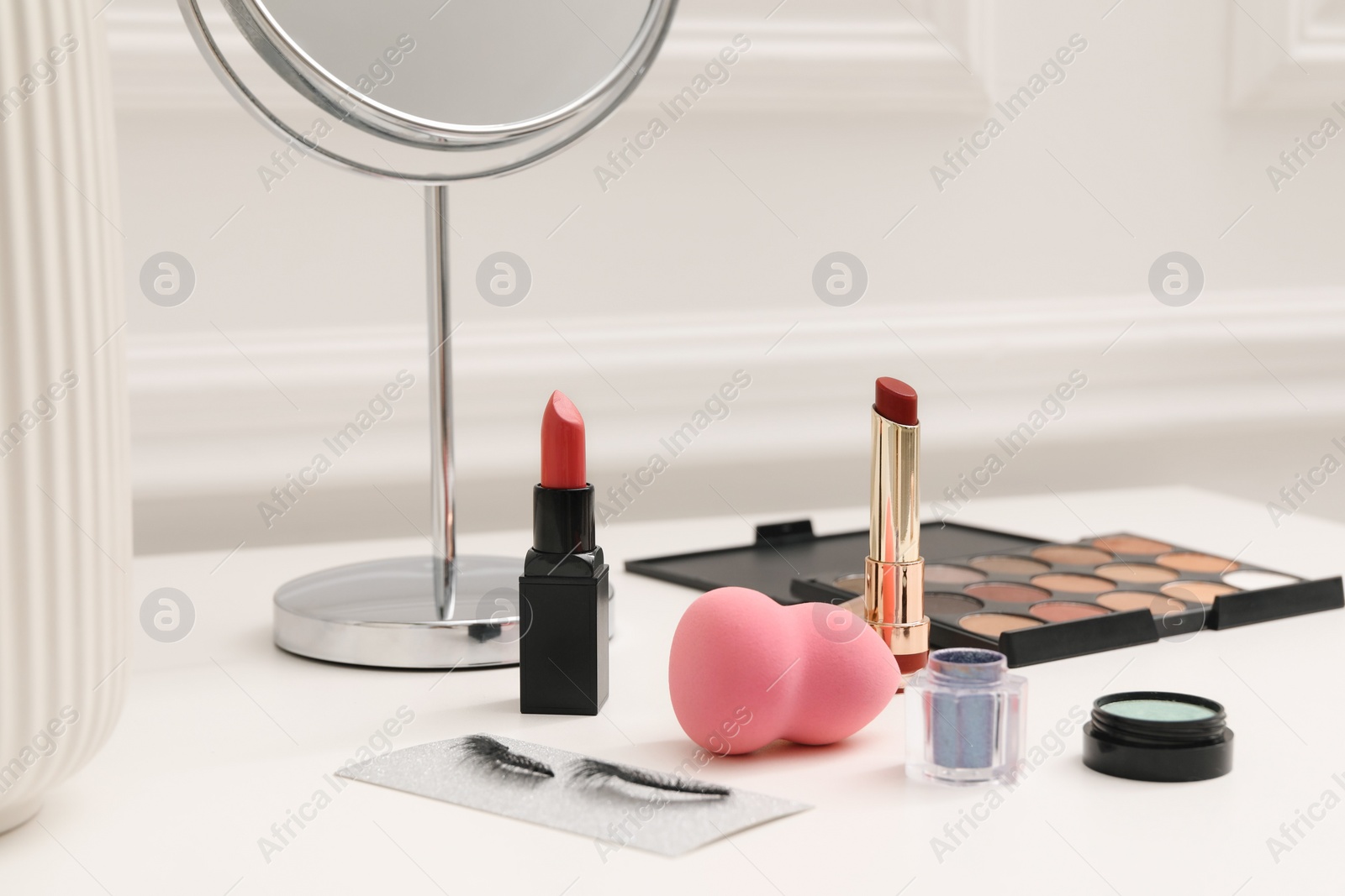 Photo of Mirror and cosmetic products on white dressing table, closeup