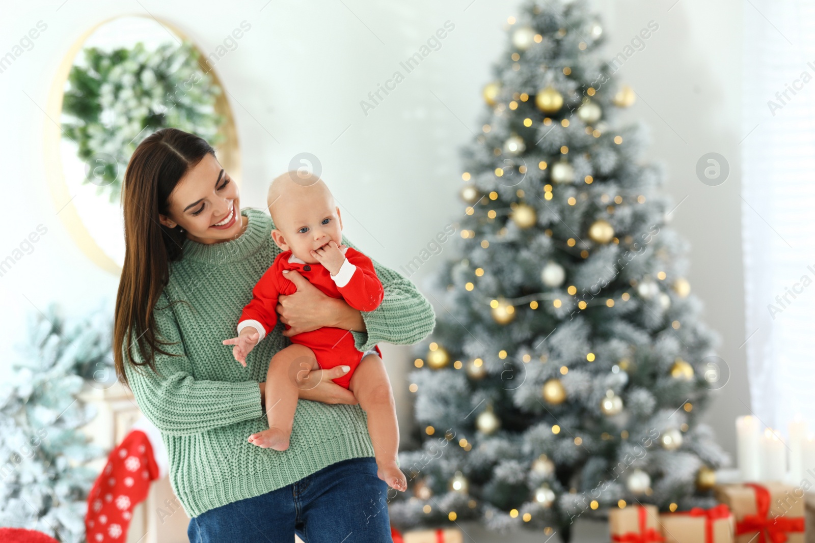 Photo of Mother with her cute baby at home, space for text. Christmas celebration