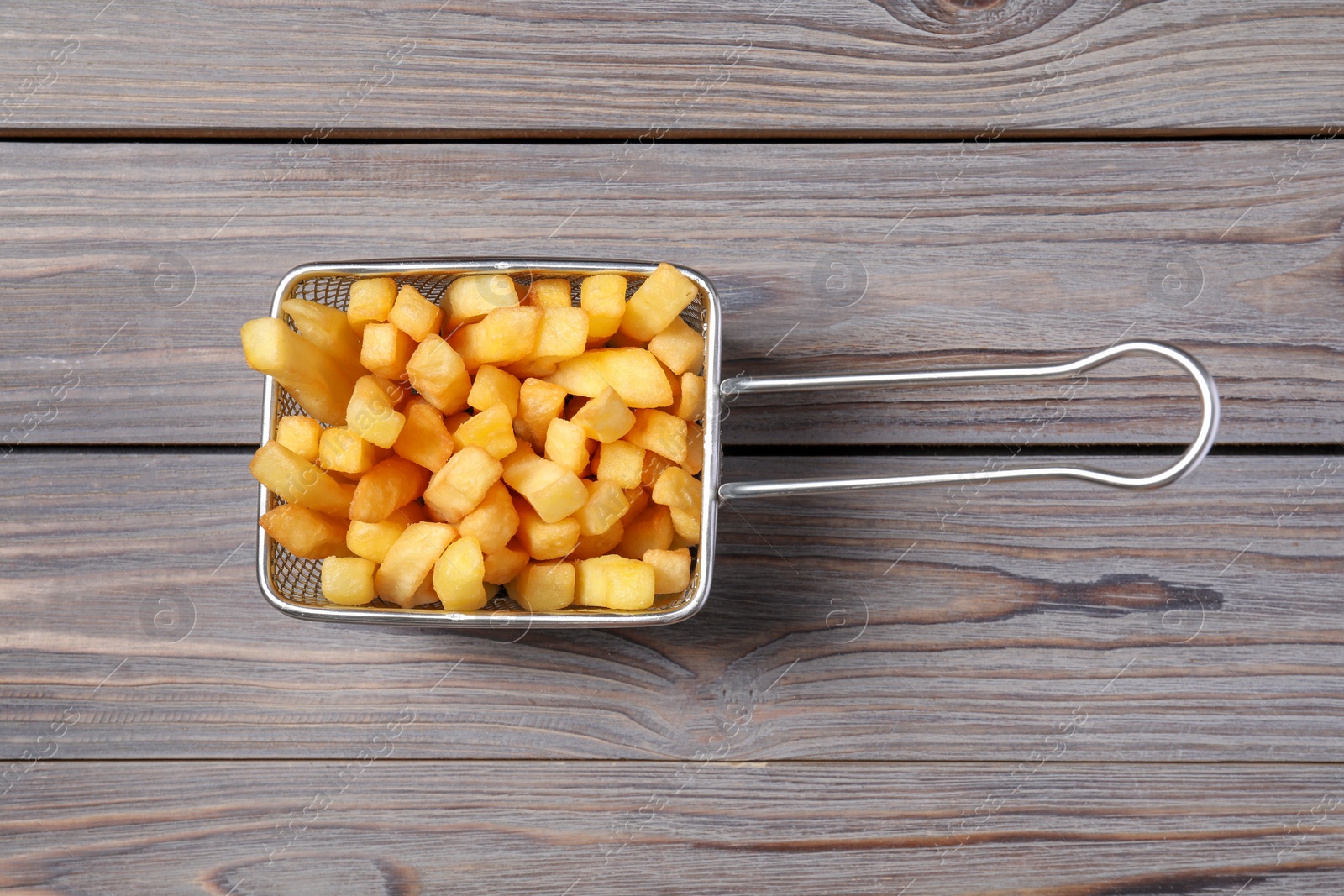 Photo of Metal basket with tasty French fries on grey wooden table, top view