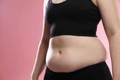 Photo of Woman with excessive belly fat on pink background, closeup. Overweight problem
