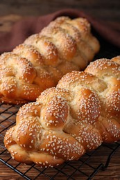 Photo of Homemade braided breads with sesame seeds on wooden table, closeup. Challah for Shabbat